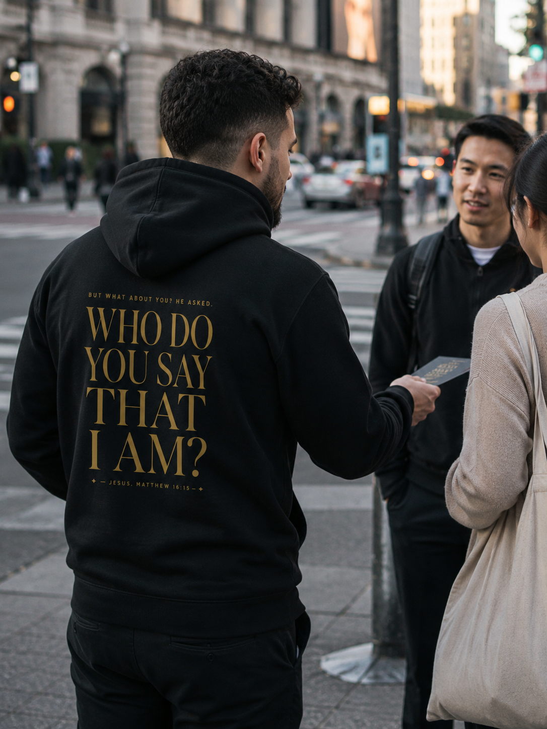 Black hoodie photographed from behind on a city street, gold back lettering reading “Who do you say that I am?” with the Matthew 16:15 citation.